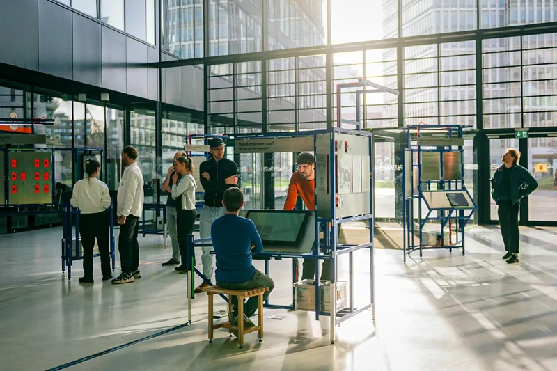 Mehrere Besucher:innen erkunden die Mitmach-Stationen der Ausstellung in einer lichtdurchfluteten Halle.